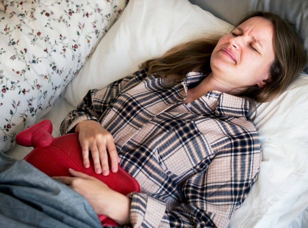 woman with cramps using a hot water bottle