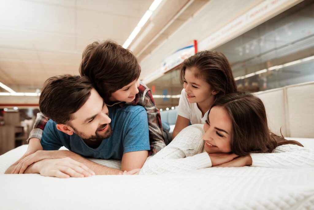 a family of four testing out a mattress in a furniture store