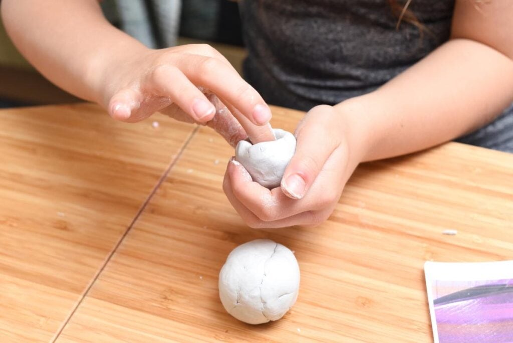 a girl forming white clay to make a craft