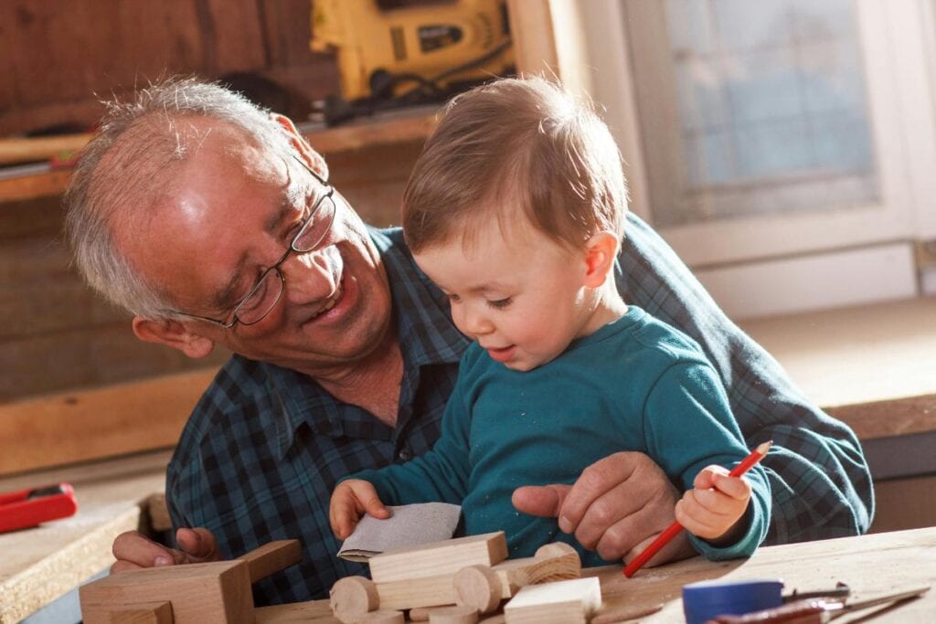 grandson and grandfather building a wooden toy together
