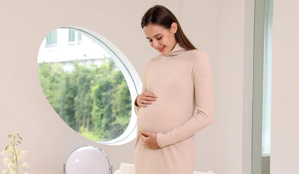 Smiling pregnant woman wearing beige maternity dress