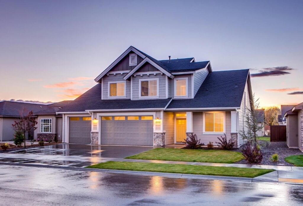 Spacious suburban home glows warmly at dusk after rain, illustrating the role of lighting and thoughtful architecture in creating welcoming spaces.