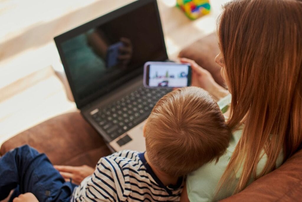 a mom and her son using a laptop and a cellphone