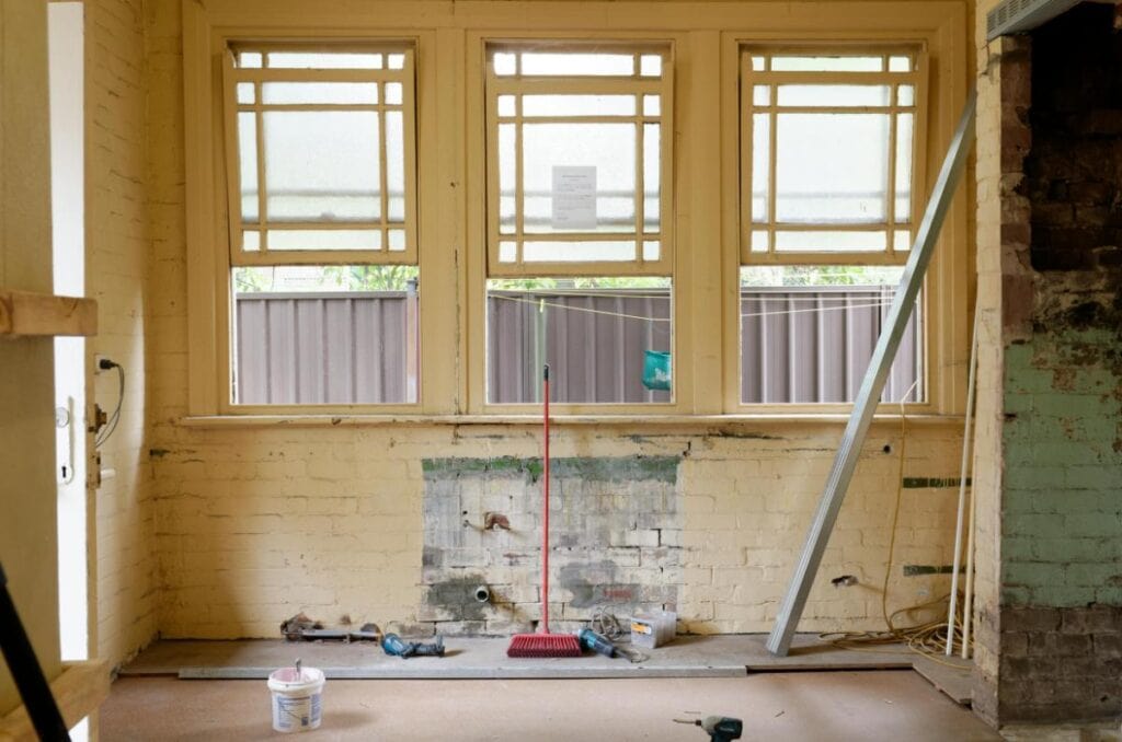 Interior of an old home mid-renovation, with exposed brick, aged windows, and tools—capturing the process of updating without erasing history.