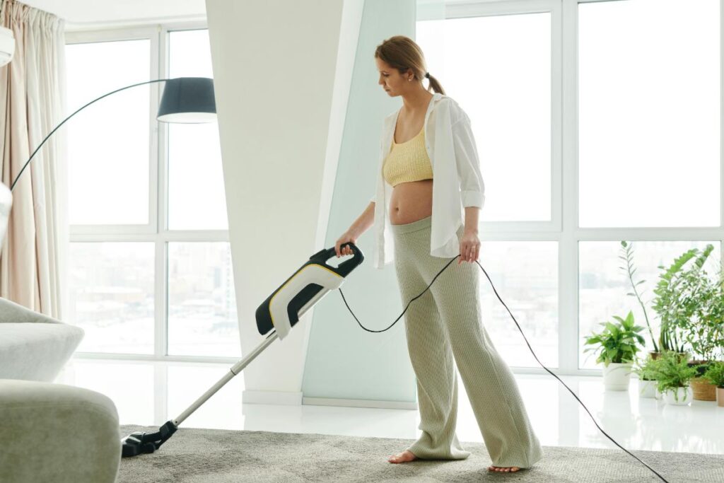 pregnant woman vacuuming the living room