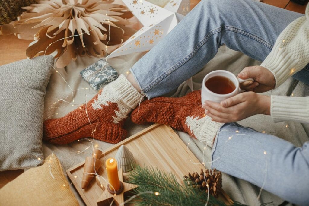 woman sitting on floor with cup of tea surrounded by holiday decor