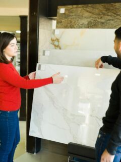 A couple examining large marble tile samples in a showroom, discussing material options for a bathroom renovation.