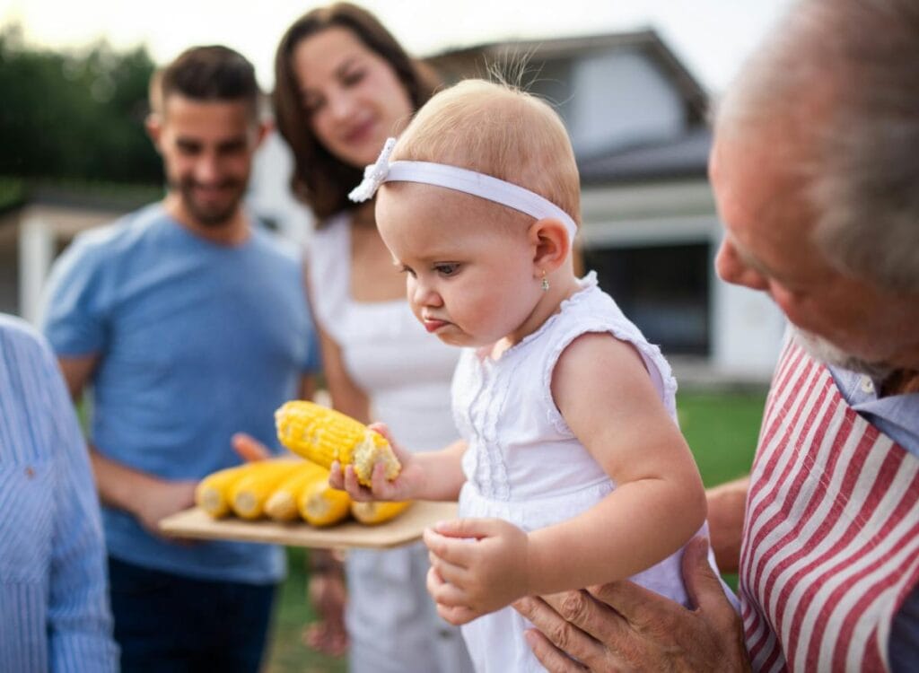 young couple looking on as grandpa holds their baby