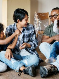 A cheerful family of four plays and laughs together amid moving boxes, celebrating the excitement of settling into a new home.