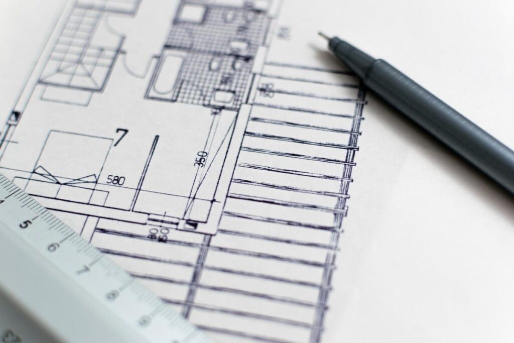 A close-up of a bathroom floor plan sketch with a mechanical pencil and ruler, symbolizing the planning stage of renovation.