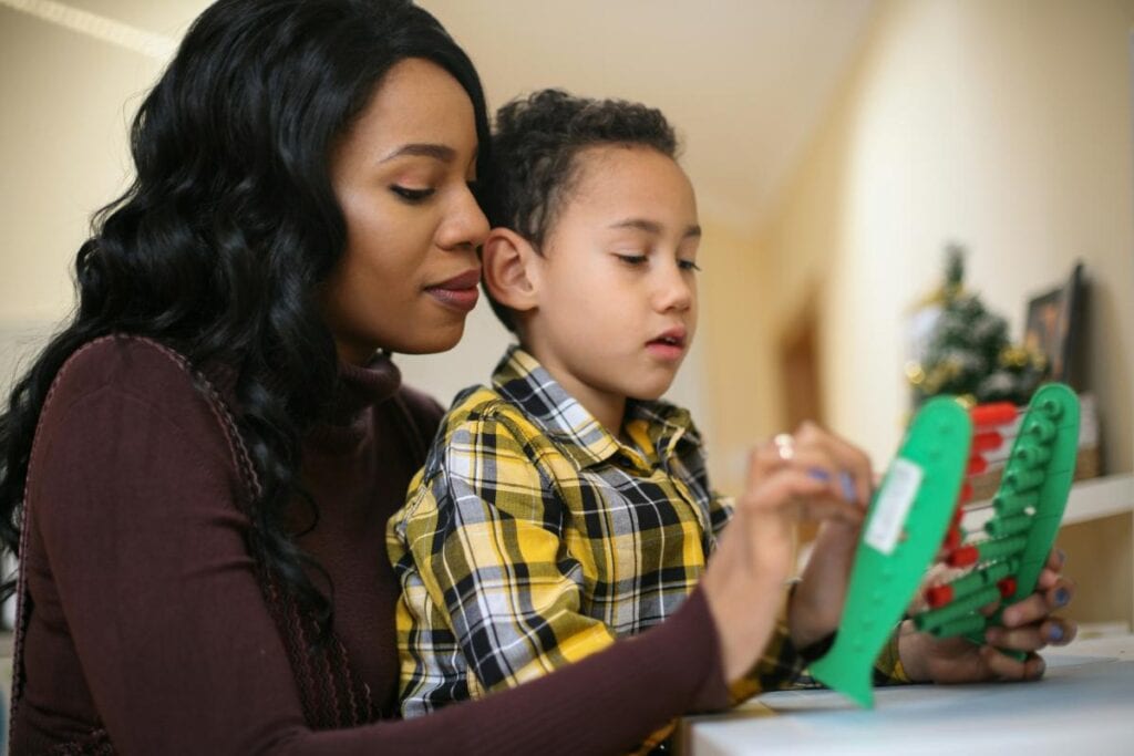 a mother teaching her young son to count using an abacus