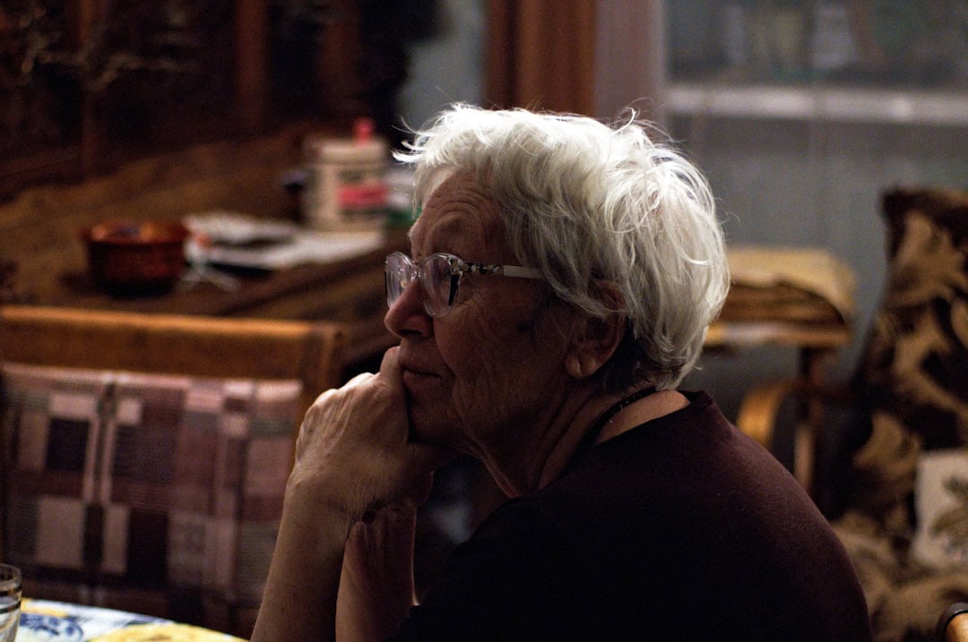 older woman sitting at the kitchen table, face resting on hands, looking thoughtful