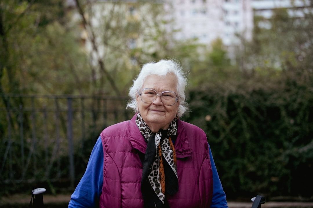 elderly woman in glasses and purple puffer vest outdoors