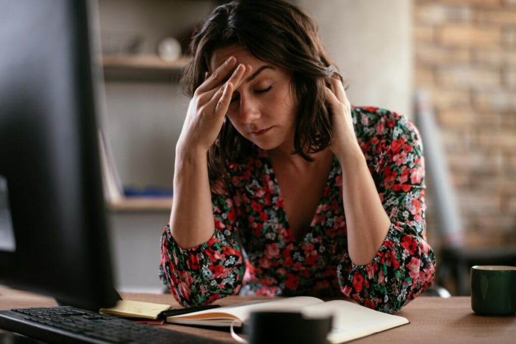 a brunette woman looking frustrated at her office desk due to burnout and employee turnover
