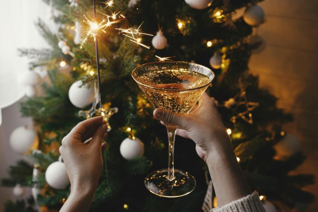 a sparkler and a glass of champagne in front of the Christmas tree