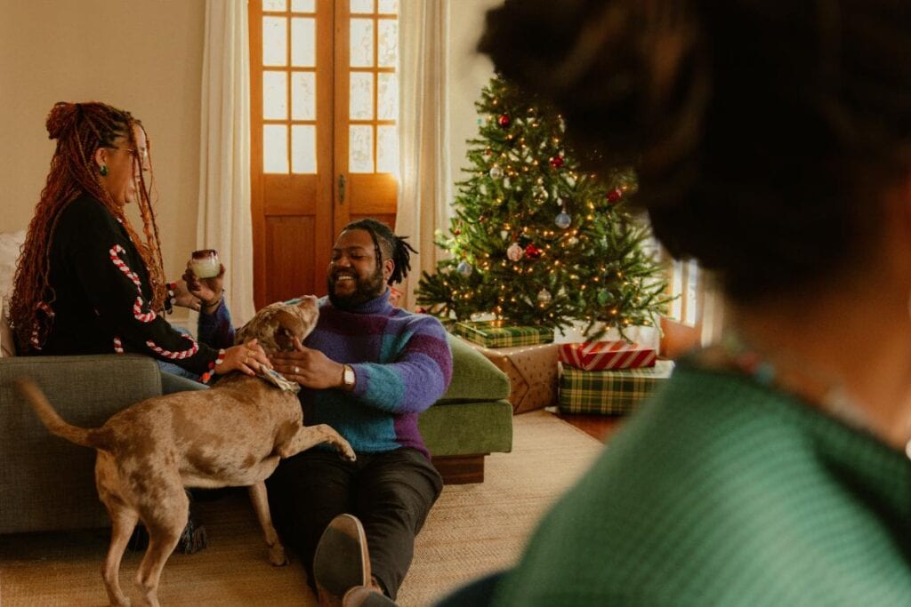 people talking and petting the dog at a holiday party