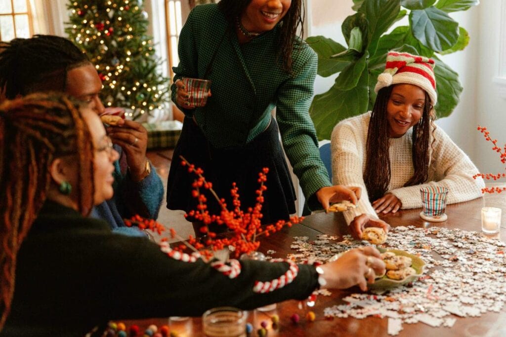a group of friends having cookies and working a jigsaw puzzle at a christmas gathering