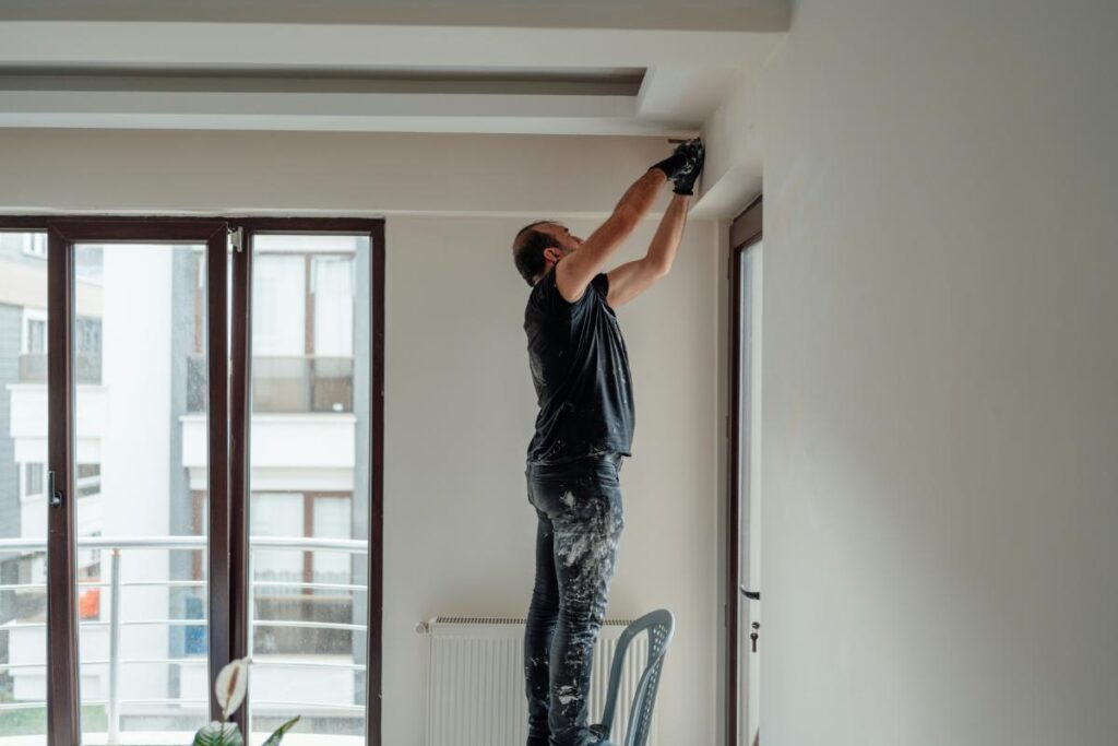 man painting walls of home white