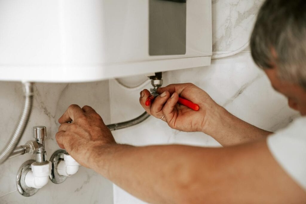 man working on water heater plumbing