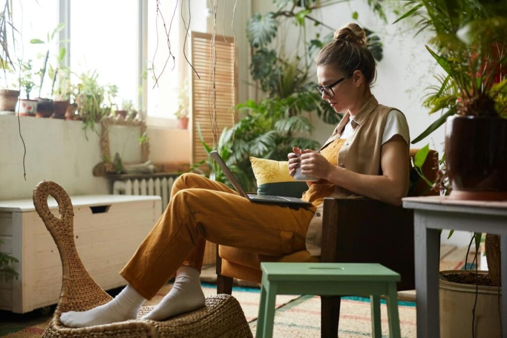 Woman in a simple bun and comfortable layered outfit working from home, showing a relaxed but put-together style.