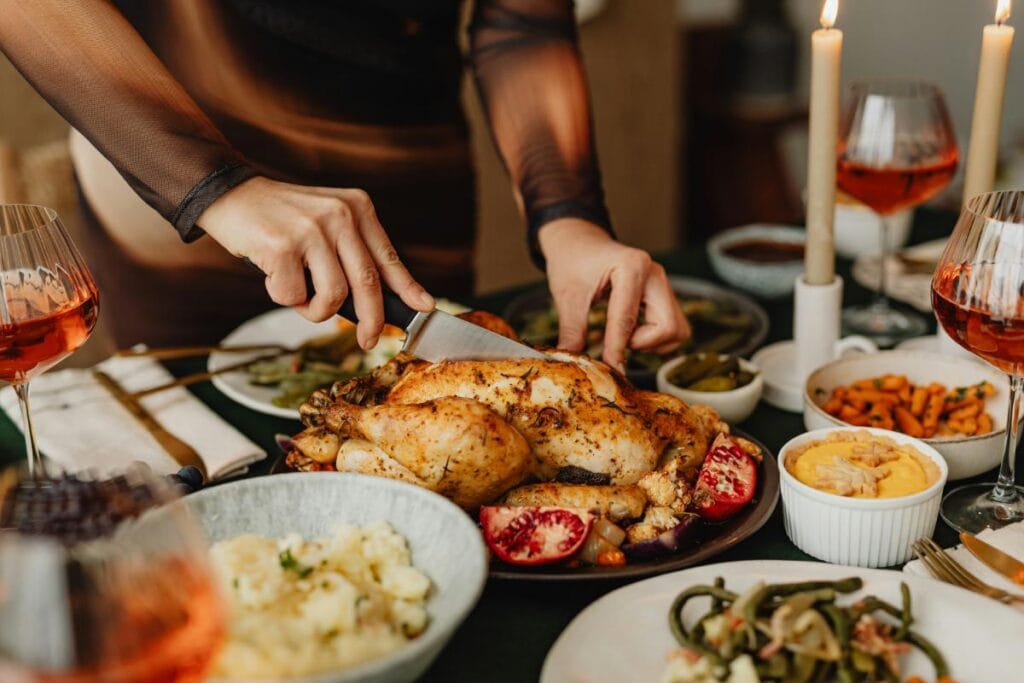 Person carving a roast chicken surrounded by classic comfort food sides at a warmly lit family meal.
