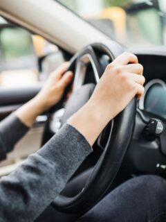 unidentifiable woman with hands placed on steering wheel