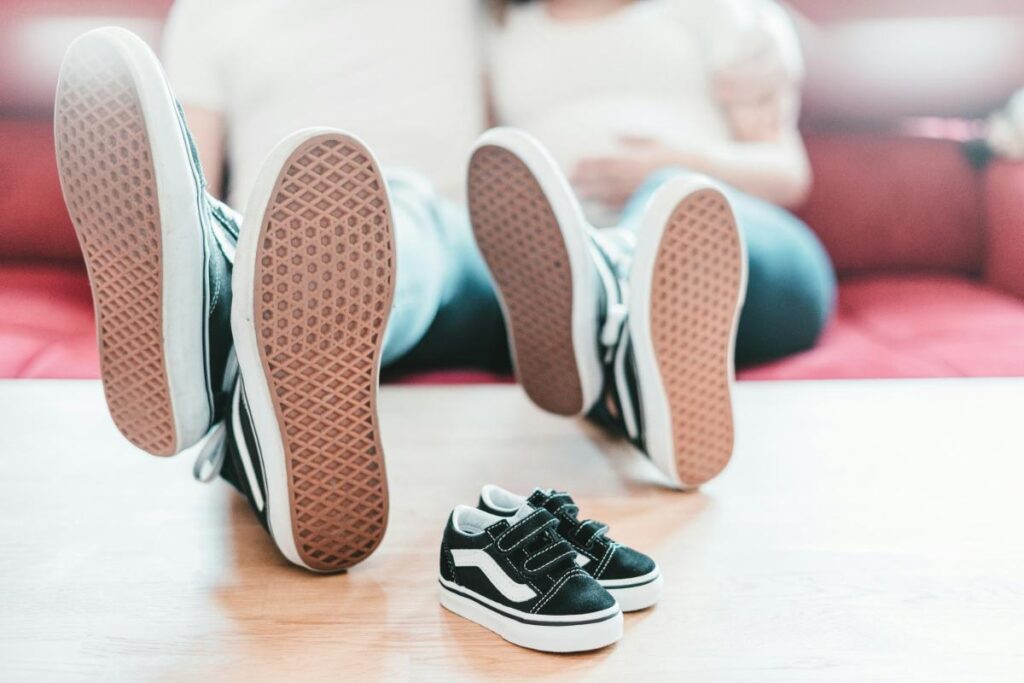 Two parents wearing low profile sneakers with baby sneakers in the foreground