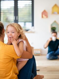 Parent hugging and playing with young child in a bright living room, highlighting bonding and supportive family routines