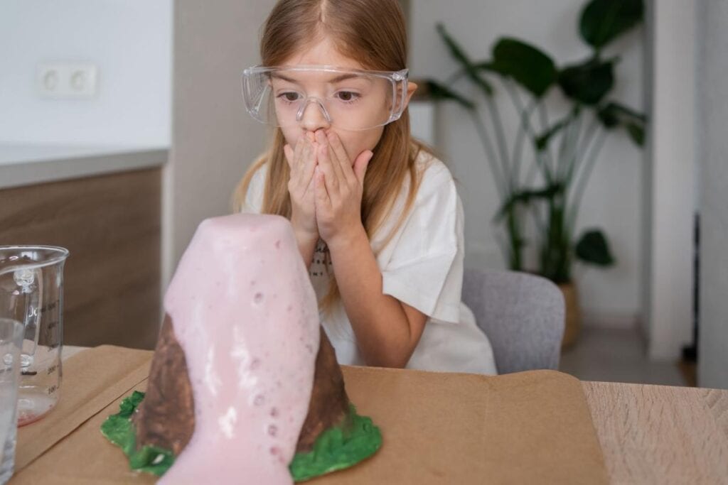  young girl watching a baking soda volcano erupt