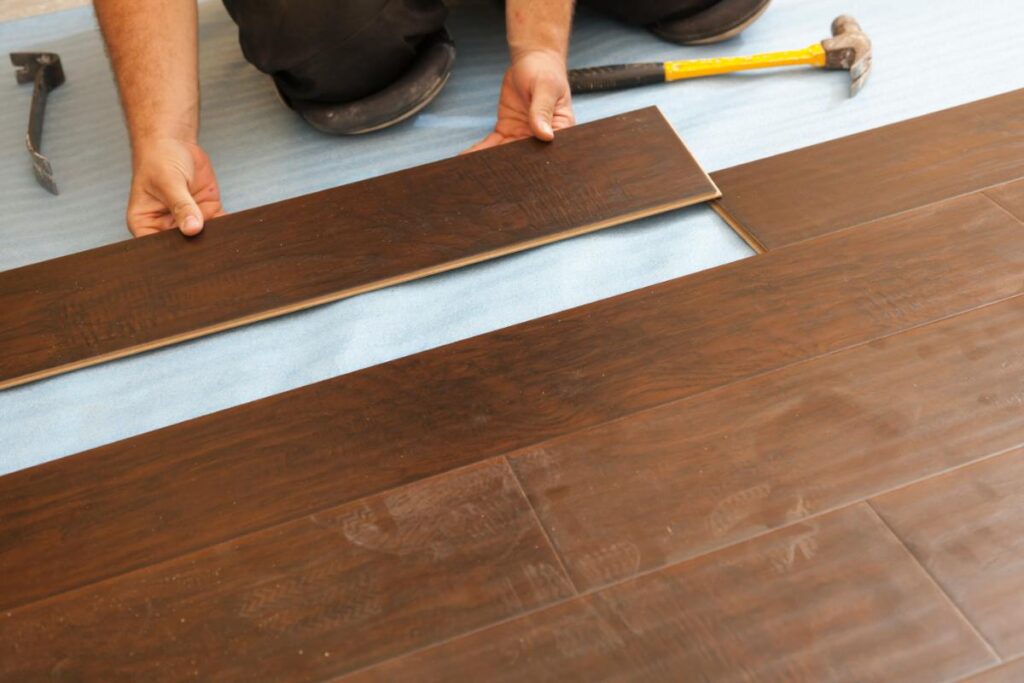 Installing laminate flooring planks by hand during floor repair or replacement.