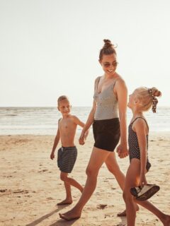 mom and her two kids walking on the beach