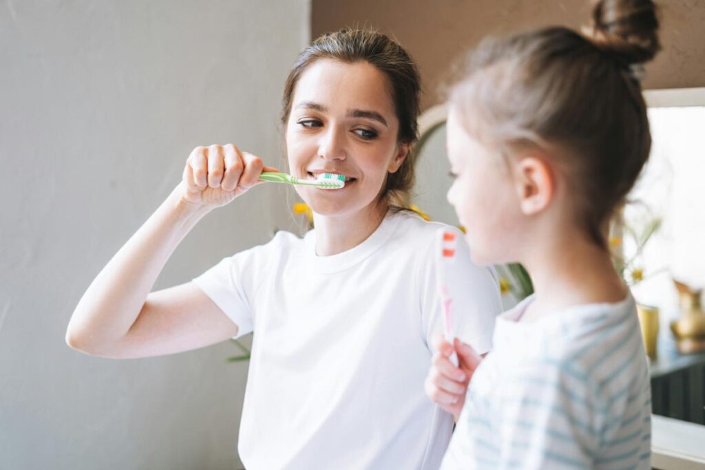 a mom showing her daughter how to properly brush teeth