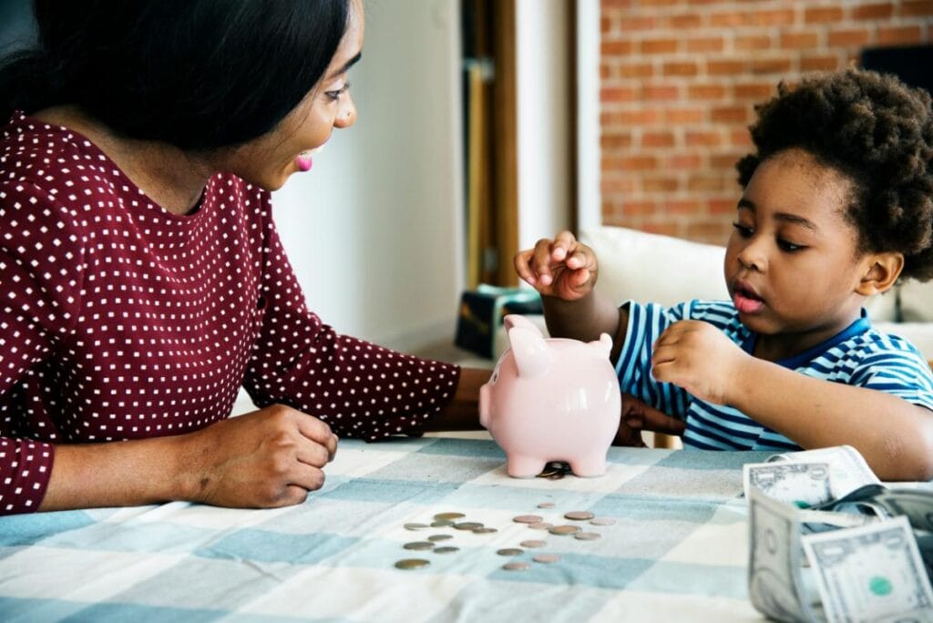 Mother and child placing coins in a piggy bank during a family lesson on saving money