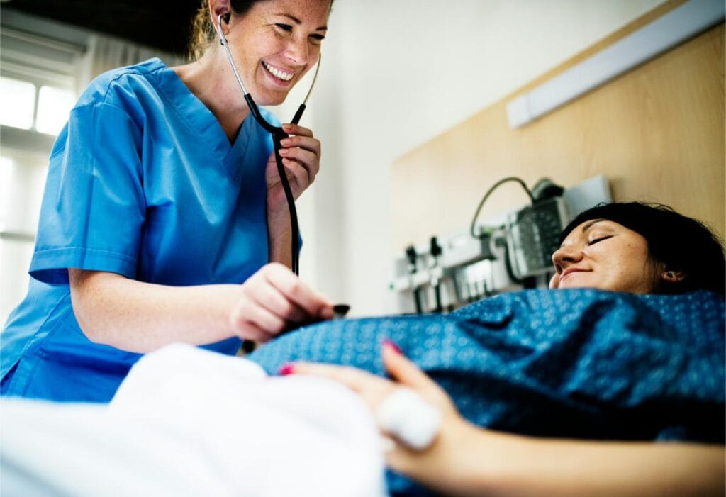 nurse using stethoscope to listen to woman's pregnant belly