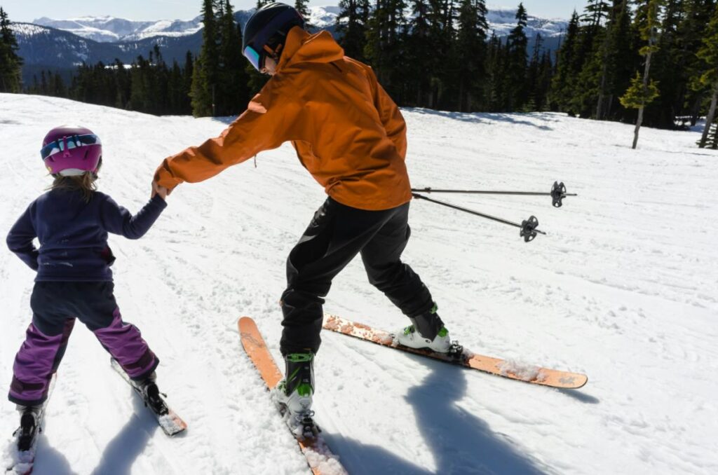 parent helping child learn to ski