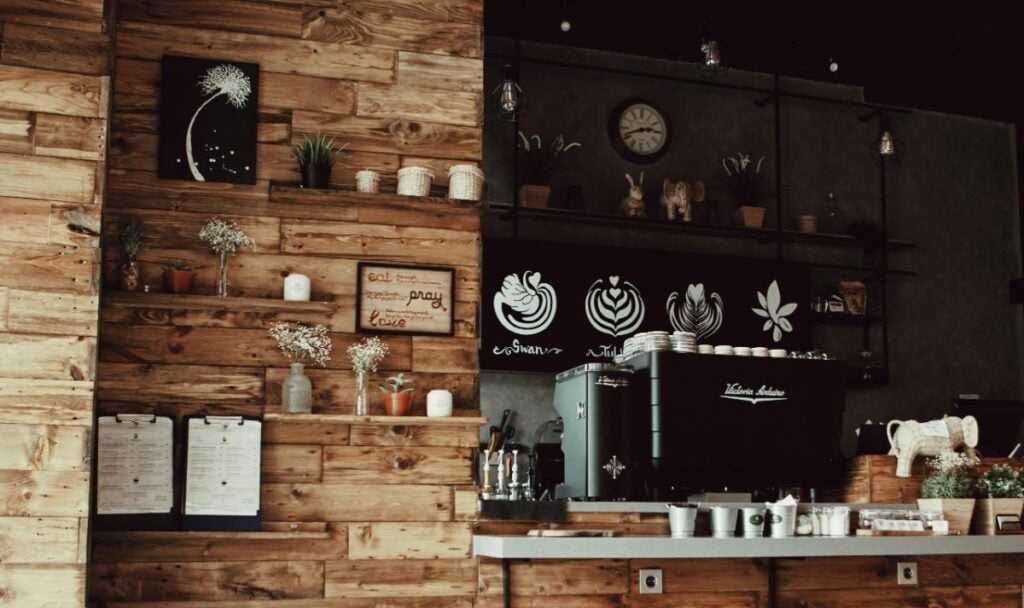 Rustic caf&eacute; interior with espresso machine, wooden shelves, and coffee d&eacute;cor, inspiring a caf&eacute;-style kitchen design.