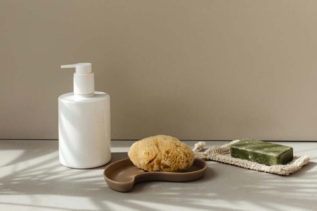 soap dispenser along with a natural sponge and bar of soap on a counter