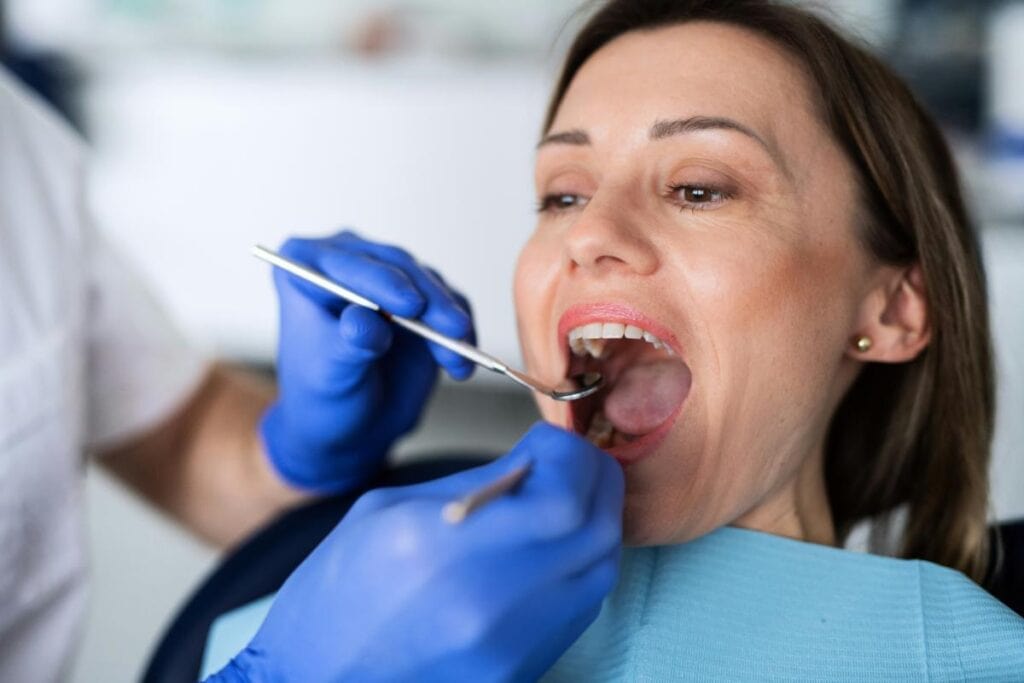 woman with open mouth getting teeth examined