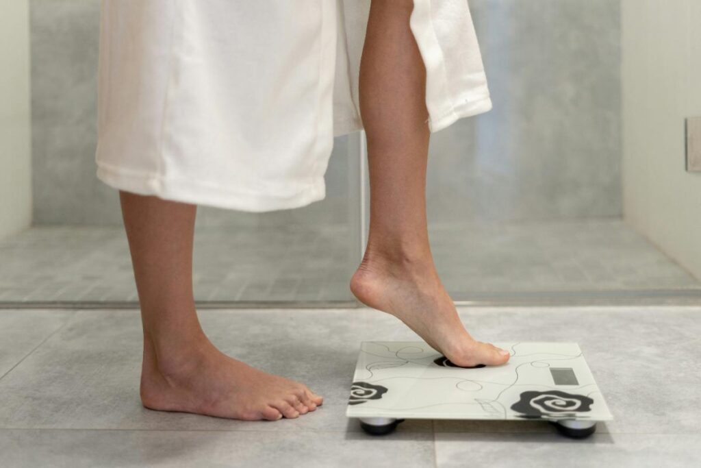 woman in a white robe stepping onto a bathroom scale