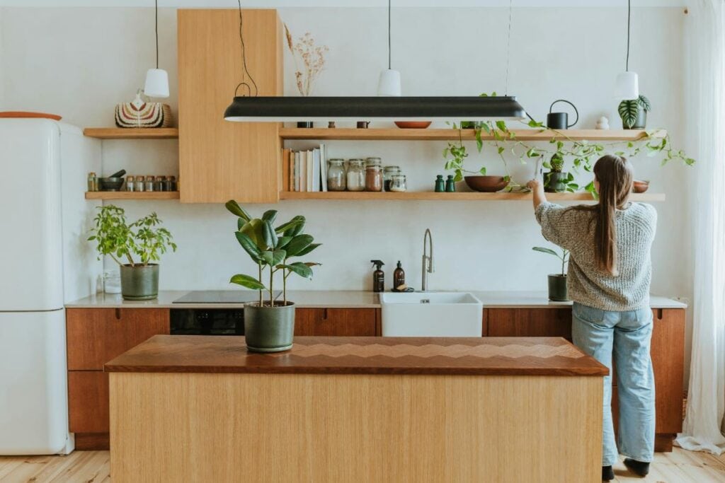 woman placing plants on a shelf in the kitchen