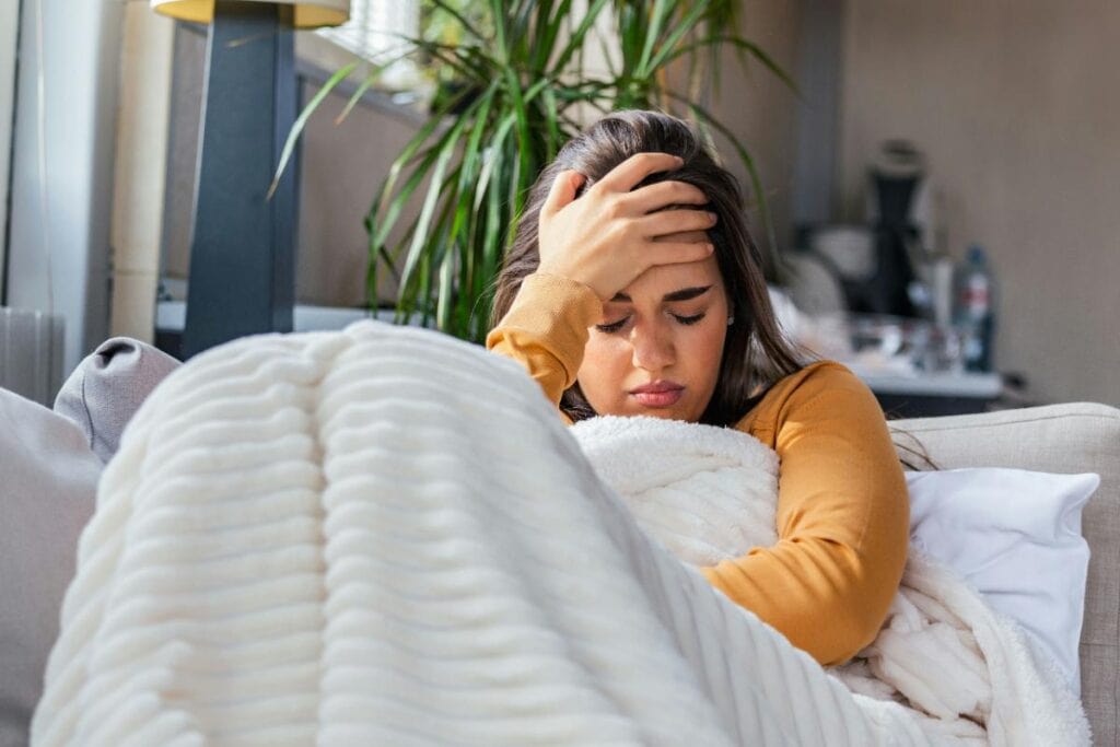 woman with a headache on the couch with a blanket