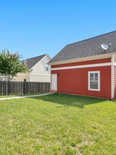 a large backyard with lots of grass and a red storage building