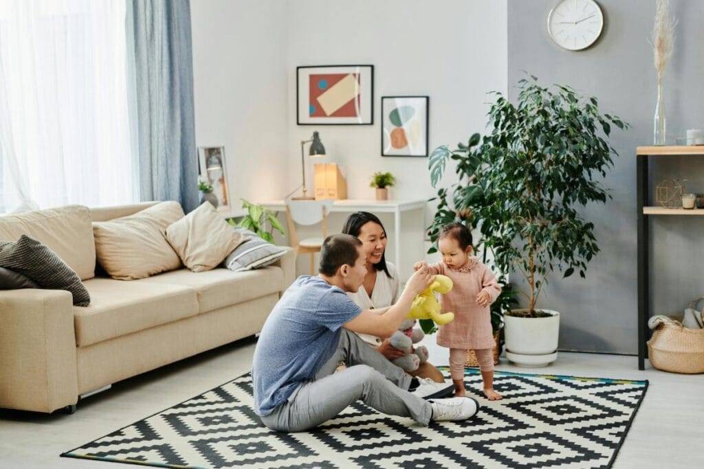 Family playing together in a bright modern living room with cozy seating, indoor plants, and a comfortable home atmosphere.