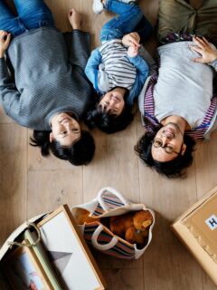 a family laying on the floor looking up at the ceiling surrounded by moving boxes