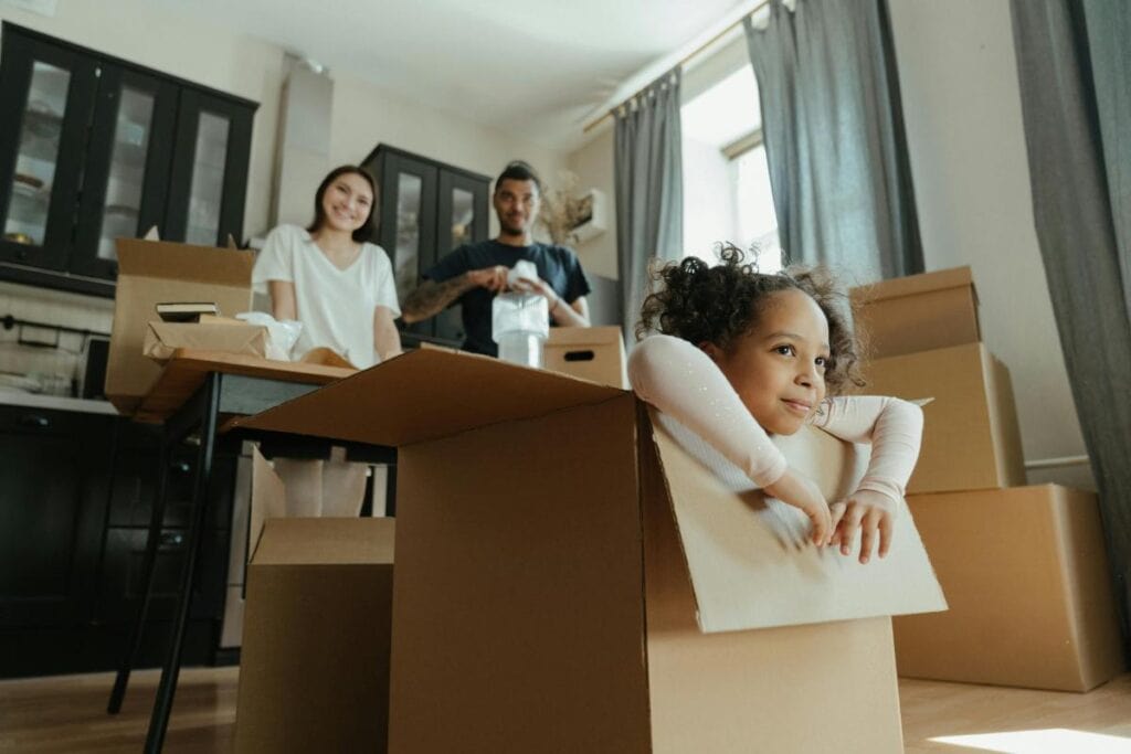 girl playing in moving box while parents smile and look on