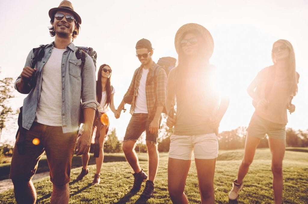 Group of friends walking together in warm sunlight with backpacks, capturing an active and social outdoor lifestyle.