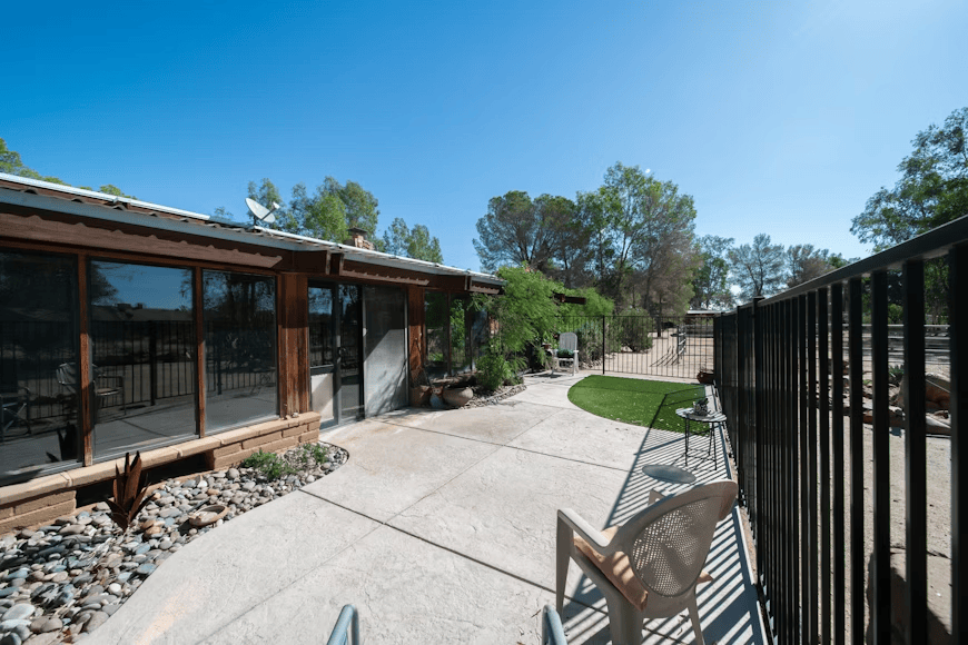 a house with a manicured backyard with small patch of grass and large patio seating area