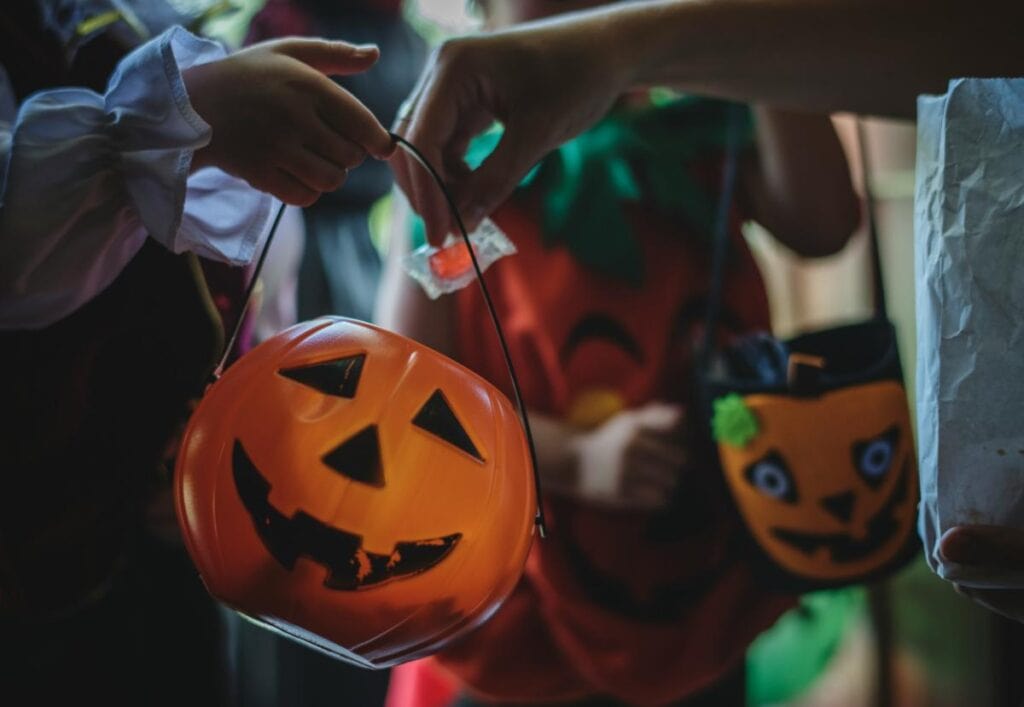 kid getting piece of candy in halloween bucket