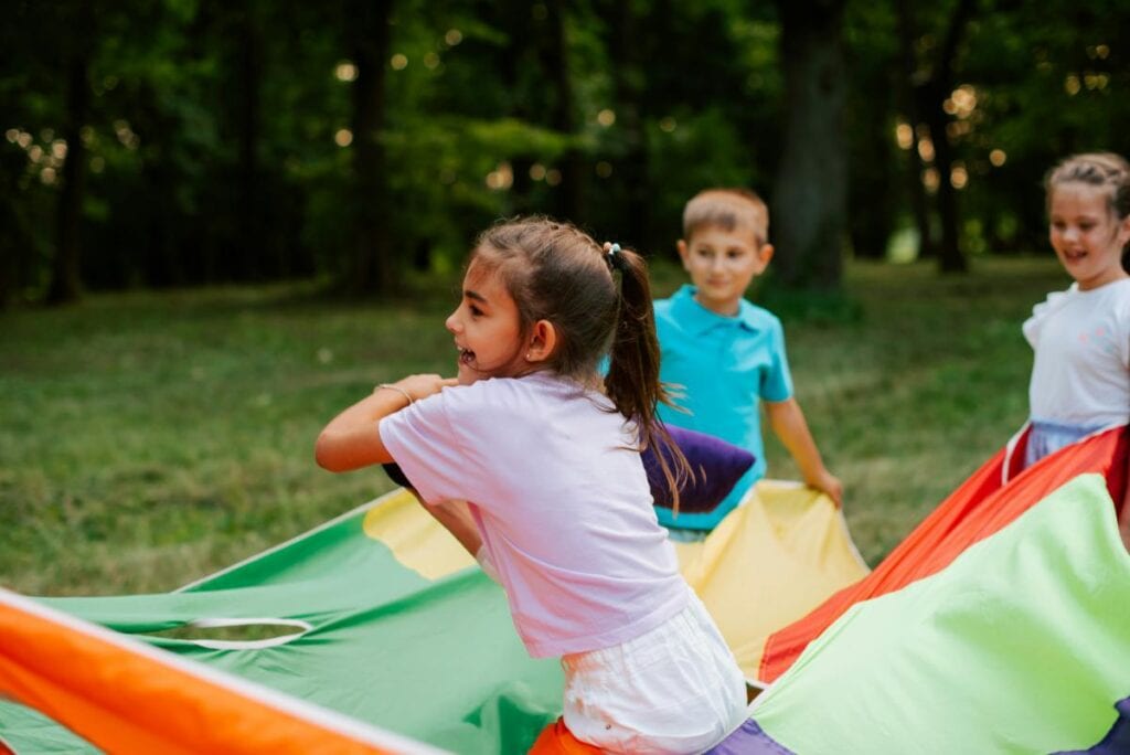 kids playing with a colorful parachute at summer camp