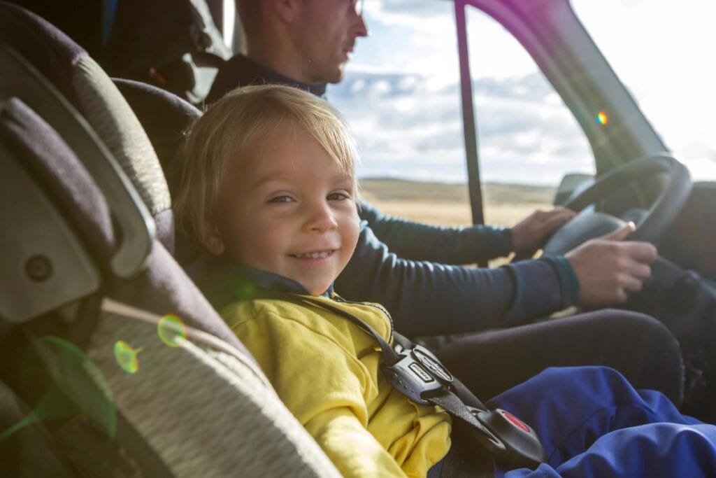 little boy in car seat riding in front of car